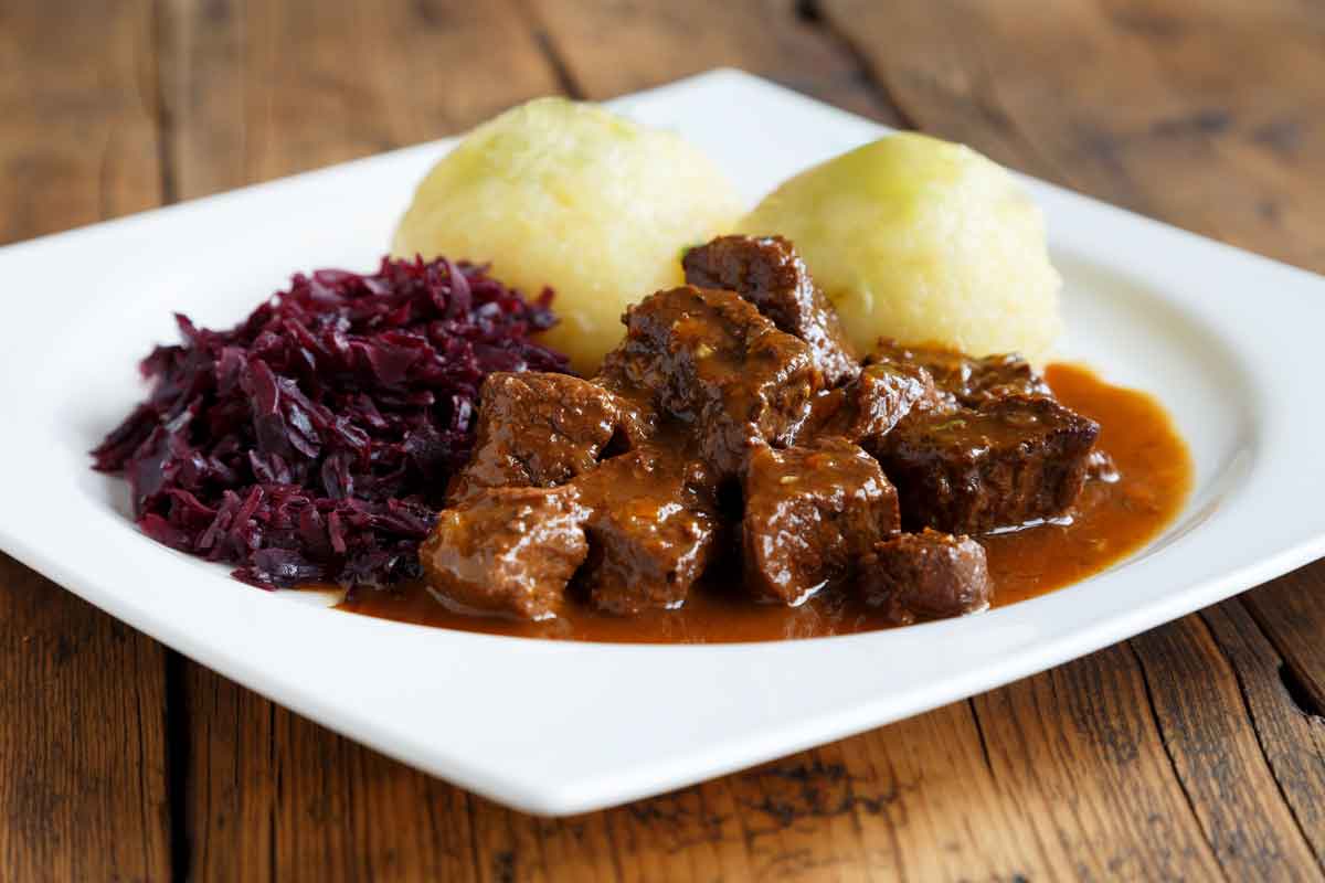 gulasch-rotkohl-thueringerkloesse-auf-einem-weissen-teller