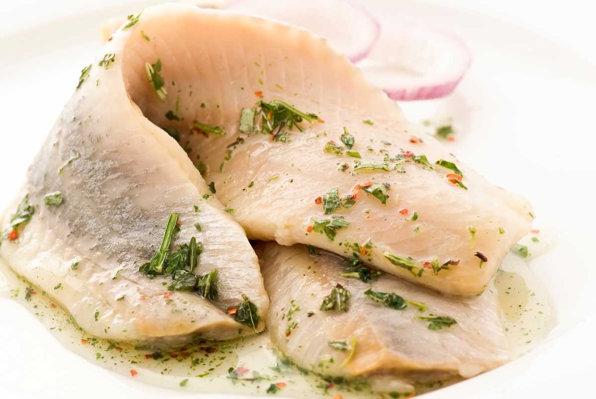 zwei Matjesfilets mit Thymian garniert und zwei Zwiebelringe als Deko