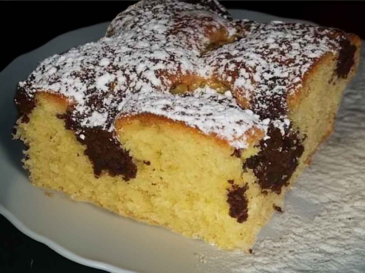 ein Stueck Blechkuchen aus Ruehrteig mit eingesunkenen Schokostreuseln