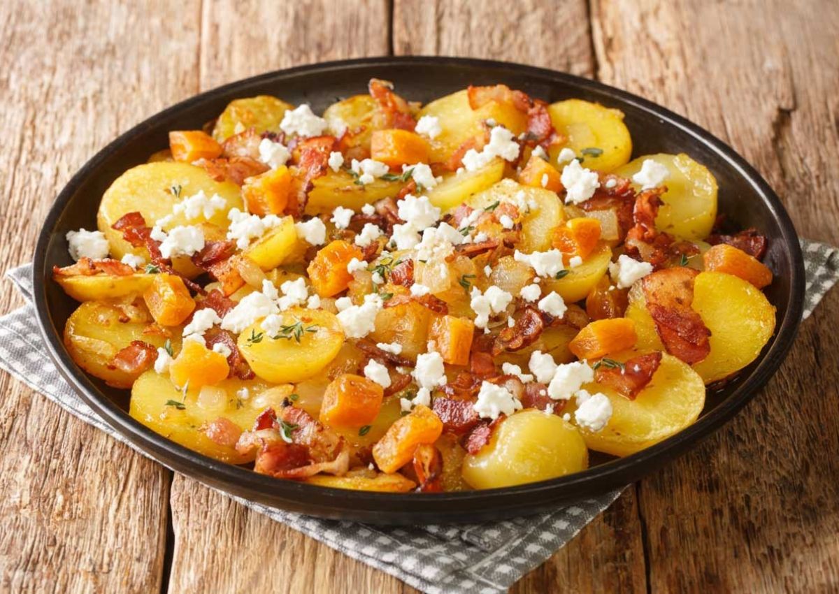 Pfanne mit goldbraunen Kartoffelscheiben; Schinkenstreifen, Basilikum und Fetastreuseln