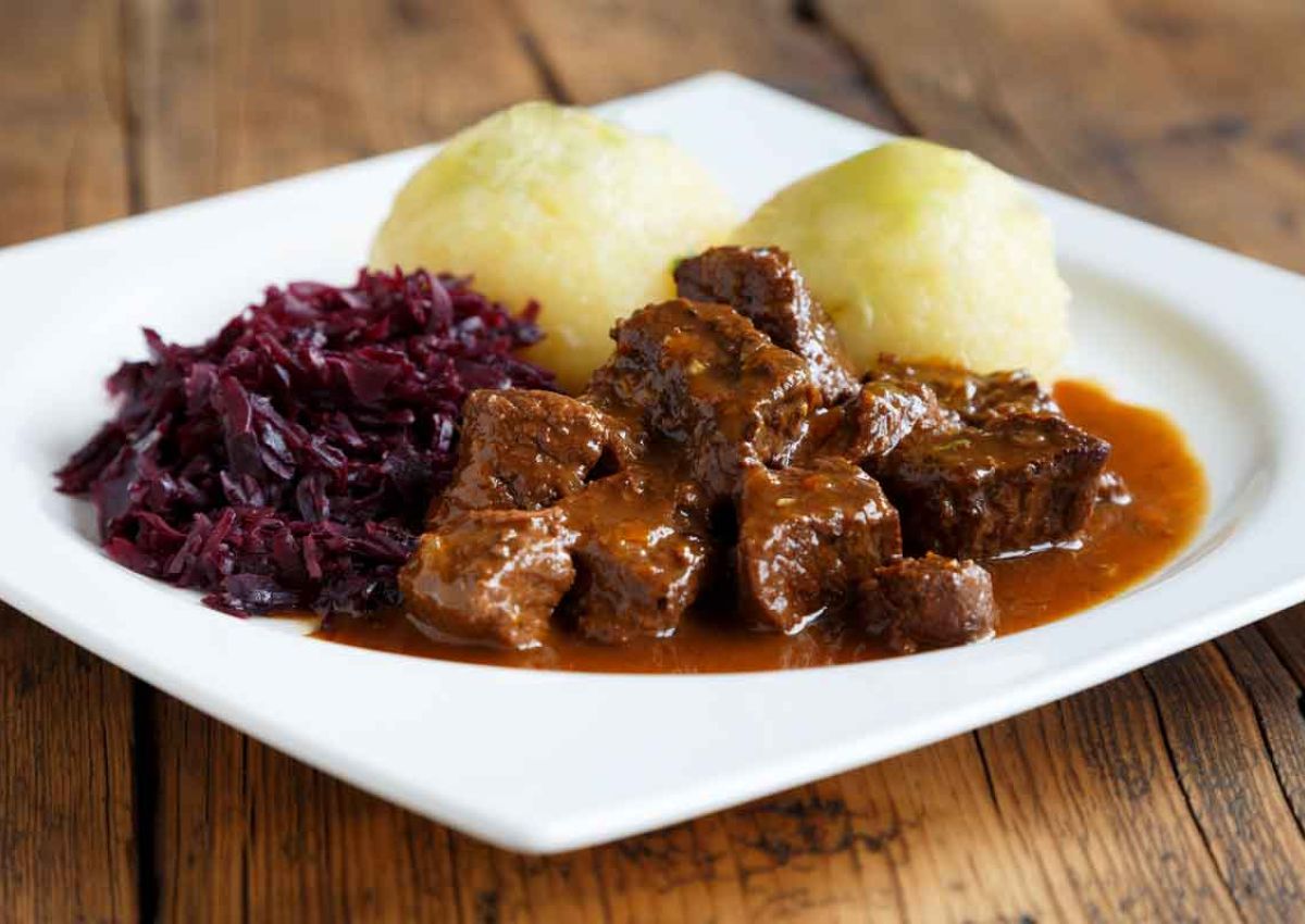 Teller mit saftigem Gulasch, Rotkraut und zwei Thueringer Kloessen