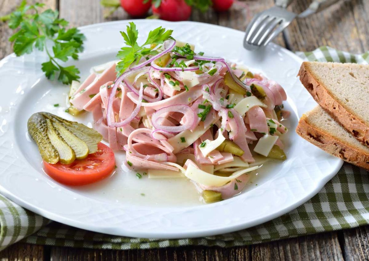 Teller mit in Streifen geschniitener Fleischwurst, Gurken, Kaese mit Petersilie, Gurken- und Tomatenscheibe dekoriert