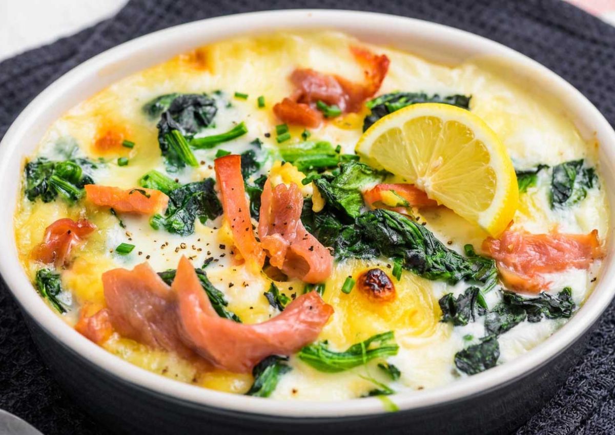 Auflaufform mit Lachs, Spinat, Kartoffeln mit Kaese gratinier, dekoriert mit einem Viertel Zitrone